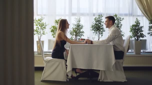 Proposta di matrimonio di un giovane bell'uomo con una bella ragazza durante un appuntamento al ristorante. La donna è sorpresa e felice, sta prendendo anello e bevendo campione per festeggiare . — Video Stock