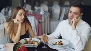 Onun kız arkadaşı Restoran masada oturan bıkkın duygu iken meşgul genç adam cep telefonla konuşuyor. Modern teknolojiler, ilişki ve can sıkıntısı kavramı.