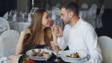 Mutlu sevgi dolu çift konuşmak ve restoranda romantik bir akşam yemeği sırasında öpüşme, elele geziyor. Sevgi ilişkisi, sevgi ve iyi yemek kavramı.