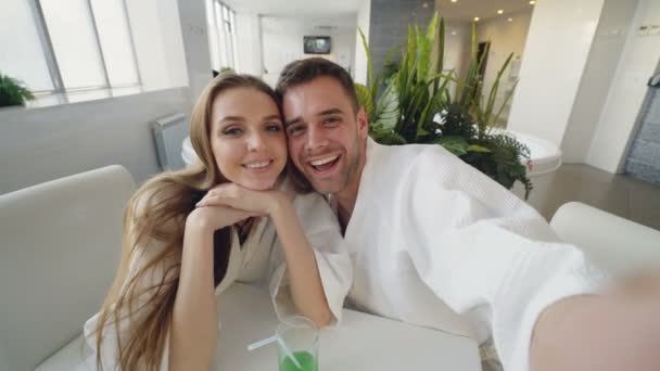 Ponto de vista tiro de casal amoroso atraente gravação de vídeo enquanto relaxa no spa dia juntos. Os jovens estão sorrindo, rindo e se beijando olhando para a câmera . — Vídeo de Stock