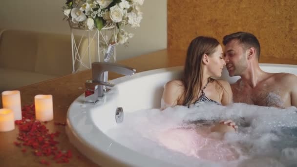 Adorable pareja joven se está divirtiendo y hablando en baño de burbujas durante la luna de miel romántica. Romance, gente feliz y amorosa concepto de estilo de vida moderno . — Vídeo de stock