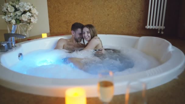 Młody Brodaty mężczyzna i jego atrakcyjne dziewczyny bawią się w wannie, rozmowa, przytulanie i śmiejąc się. Romantyczny związek, odnowy biologicznej i koncepcja szczęśliwych ludzi. — Wideo stockowe