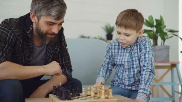 Liefdevolle vader is schaken met zijn kleine kind, leer hem regels en praat met hem. Het verhogen van kinderen, intellectuele spellen en gelukkige jeugd concept. — Stockvideo