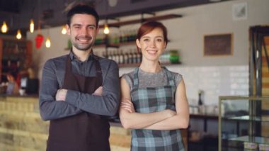 Mutlu yakışıklı garsonların geçti, gülen ve kameraya bakarak elleri ile yeni kafe içinde duruyor. Güzel insanlar ve yemek servis kavramı.