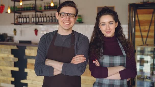 Portret van twee koffie huis eigenaren aantrekkelijke jonge mensen permanent binnen koffieshop, glimlachend en camera kijken. Succesvolle start-up en mooie mensen concept. — Stockvideo