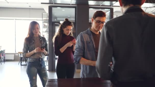 Jongeren staan in lijn afhaalmaaltijden koffie kopen en betalen met mobiele telefoon in café in de ochtend. Succesvolle business en moderne bankwezen concept. — Stockvideo