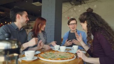 Kızlar ve çocuklar en iyi arkadaş sohbet ve dilim üzerinden büyük tabak büyük lezzetli pizza alarak mutlu. Dostluk, iletişim ve pizzahouse kavramı.