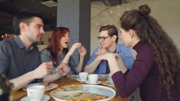 Příjemný mužský a ženský kolegové jsou jíst pizzu v kavárně mluvit a baví spolu během polední přestávky. Konverzace, chutné jídlo a šťastných lidí koncepce. — Stock video