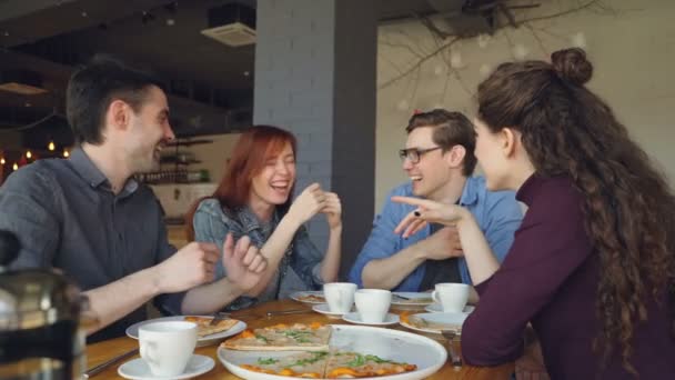 Amigos cercanos están compartiendo historias divertidas haciendo gestos y riéndose mientras almuerzan en la cafetería moderna. Emociones positivas, gente feliz y sabroso concepto de comida . — Vídeos de Stock