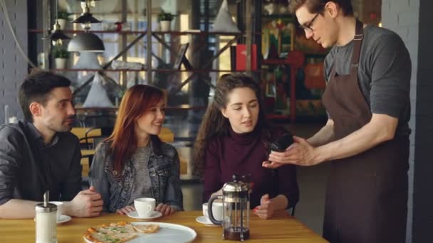 Mujer bonita joven está pagando con teléfono inteligente para la comida en la cafetería después del almuerzo con amigos. Tecnología moderna, pago sin contacto y concepto de comer fuera . — Vídeos de Stock