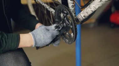 Yakın çekim bir kırık bisiklet pedalla anahtar atölye ile tamir koruyucu eldiven erkek elinde kadeh. Meslek, insanlar ve bakım kavramı.