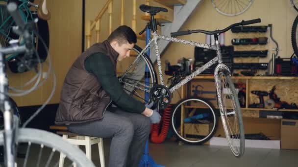Maître expérimenté est la réparation de la bande de roulement de vélo avec clé d'outils spéciaux tout en travaillant en atelier avec des pièces de rechange et de l'équipement. Personnel et concept d'entretien . — Video