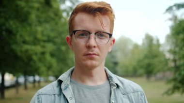 Yeşil Park 'ta tek başına duran gözlüklü genç adam yavaş hareket ediyor.