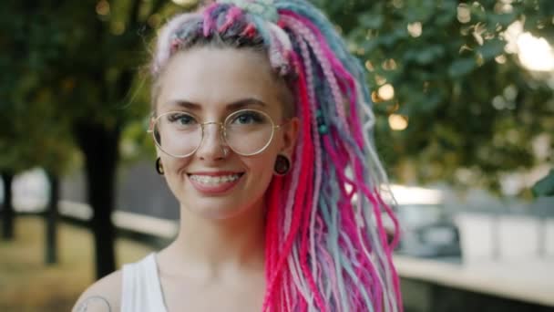 Close-up portrait of joyful woman with bright hair piercing and braces in park — Stock Video