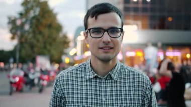 Modern şehrin yaya sokağında gülümseyen gözlüklü mutlu adam.