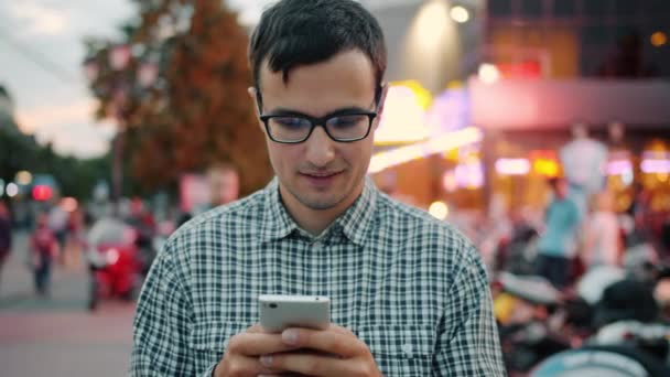 Aluno alegre sorrindo usando smartphone segurando dispositivo tocando tela ao ar livre — Vídeo de Stock