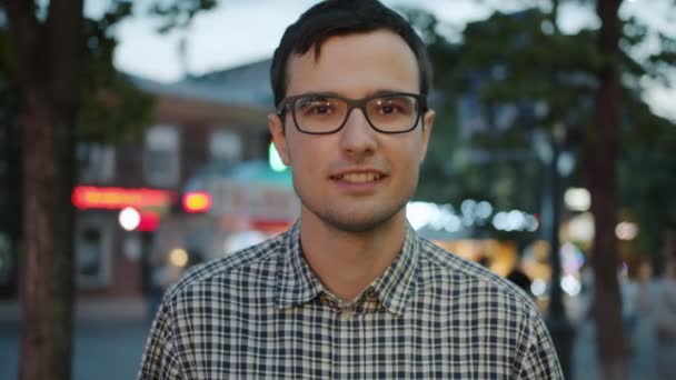 Vrolijke jongeman met een vrolijke glimlach in de stad straat in de avond — Stockvideo