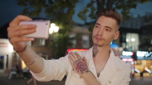 Getatoeëerde jonge man nemen selfie buiten met smartphone 's nachts in de zomer — Stockvideo