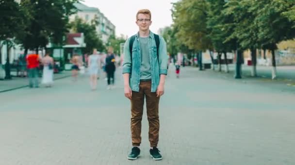 Zoom in time lapse of attractive guy student outdoors in busy urban street — Stockvideo
