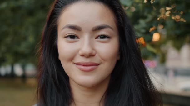 Slow motion of attractive Asian lady smiling outside in park on summer day — 비디오