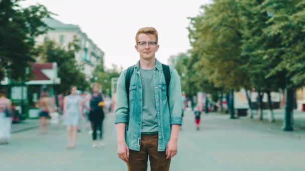 Проміжок часу чоловічого туриста, що стоїть на міській вулиці на тротуарі, дивлячись на камеру — стокове відео