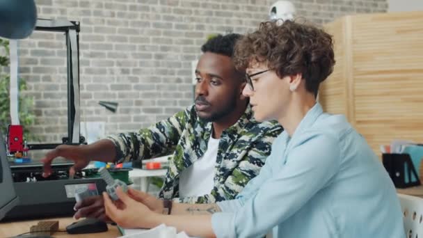 Fille et gars concevant des détails pour robot en utilisant l'ordinateur et l'imprimante 3D au travail — Video