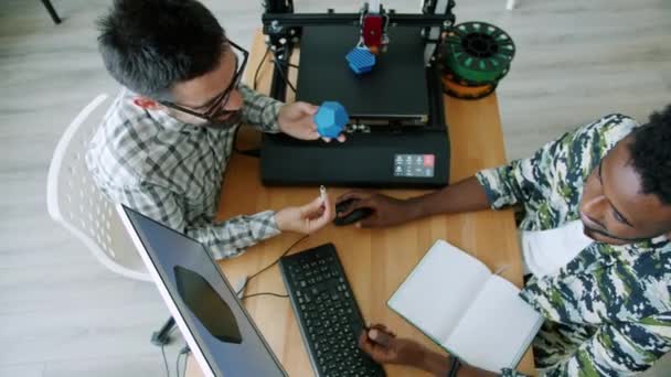 Ingenieros alegres fabricación 3d impreso detalle utilizando el ordenador hablando en la oficina — Vídeos de Stock