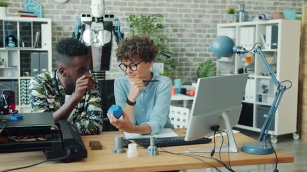 Especialistas jóvenes que hacen detalles impresos en 3D para el robot hablando trabajando en la oficina — Vídeos de Stock