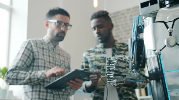 Trage beweging van jongens testen robot met tablet, slimme machine bewegende arm — Stockvideo