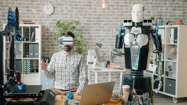 Επιστήμονας σε vr γυαλιά δοκιμή ρομπότ στο γραφείο, μηχανή επαναλαμβανόμενες κινήσεις — Αρχείο Βίντεο