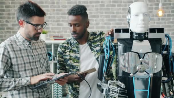 Desarrolladores construyendo y probando robot en la oficina usando tableta en interiores — Vídeos de Stock