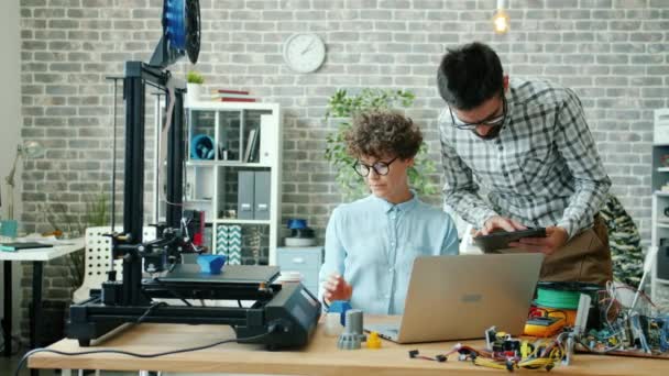 Uomo e donna che utilizzano tablet, laptop e stampante 3d in ufficio parlando di lavoro — Video Stock