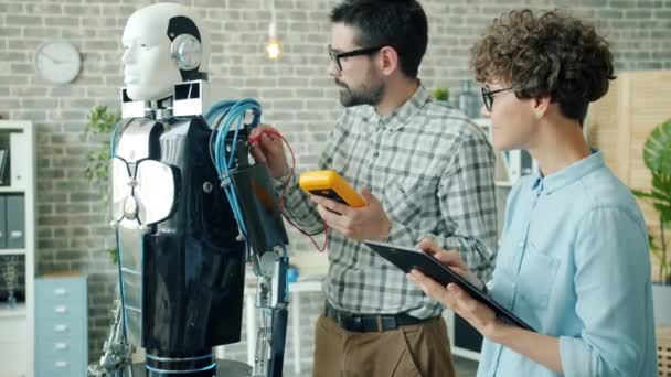 Cientistas verificando robô com dispositivos eletrônicos usando tablet na sala de escritório — Vídeo de Stock