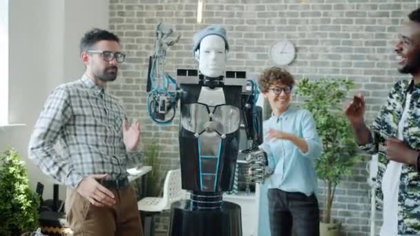 Ingenieros robóticos gozosos bailando con un robot inteligente parecido a un ser humano en la oficina — Vídeos de Stock