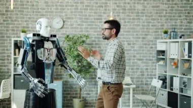 Ofis odasında akıllı robotla dans eden mutlu müteahhit işte eğleniyor.