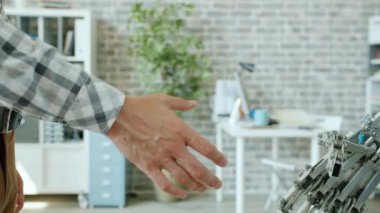 İnsan ve akıllı robotun ofis odasında el sıkışırken yakın plan çekimleri.
