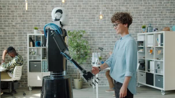 Movimiento lento del robot inteligente y la joven dama estrechando la mano en la oficina en el trabajo — Vídeos de Stock