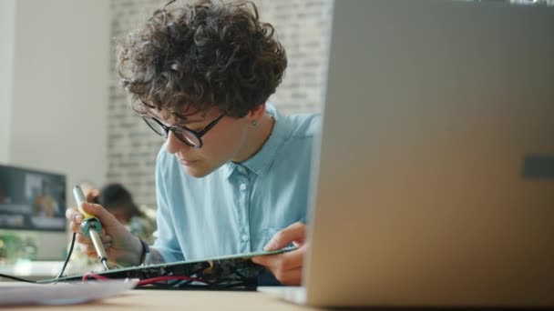 Aantrekkelijke vrouw die soldeerbout op kantoor gebruikt om microschakelingen op het werk te repareren — Stockvideo