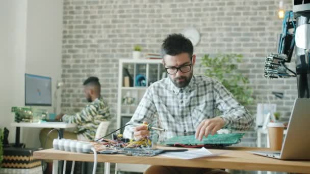 사무실에서 납땜하는 다리미를 사용하여 로봇용 메인보드를 만드는 젊은 전문가 — 비디오