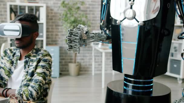 Afro-Amerikaanse man in ar bril testen robot bewegende hand in werkplek — Stockvideo