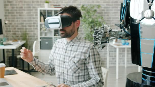 Wetenschapper in virtual reality glazen bewegende hand en robot herhalende bewegingen — Stockvideo