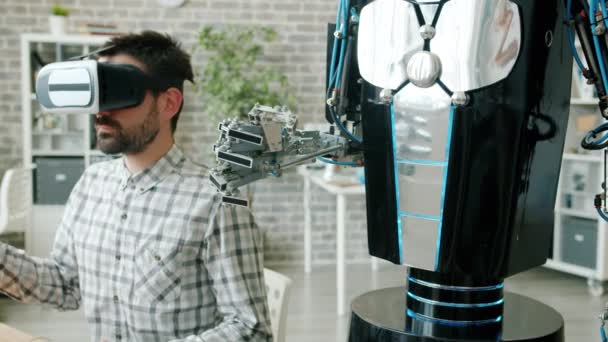 Człowiek i robot ramię robi te same ruchy, facet w okularach VR maszyny do testowania — Wideo stockowe