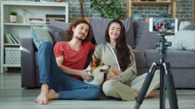 Birkaç vlogger akıllı telefon kullanarak evde Corgi Dog 'u okşarken video kaydediyor.