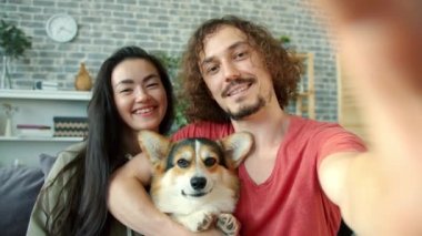 Neşeli kız ve erkek, Corgi Dog 'la selfie çekiyorlar. Komik suratlar yaparak eğleniyorlar.