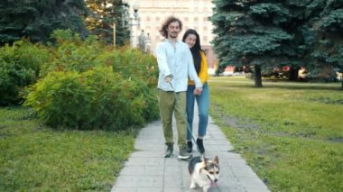 Şehir parkında Corgi köpeğiyle yürüyen çok ırklı mutlu çift.