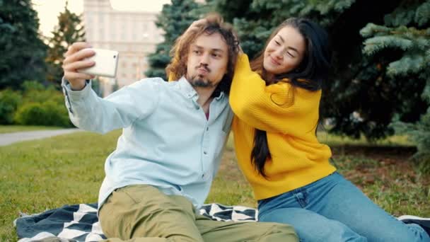 Hermosa pareja multiétnica divirtiéndose al aire libre tomando selfie con teléfono inteligente — Vídeo de stock