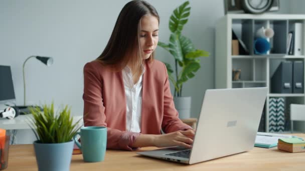 Porträt einer schönen Geschäftsfrau, die mit einem lächelnden Laptop am Schreibtisch sitzt — Stockvideo