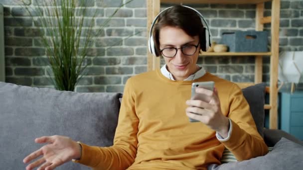 Slow motion of cheerful young man melomaniac enjoying music and using smartphone — Stock Video