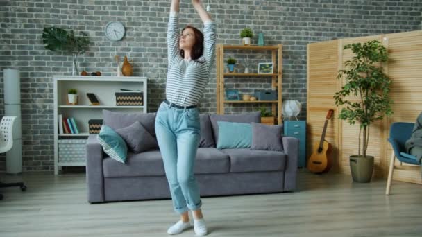 Jovencita alegre está bailando en casa cuerpo en movimiento disfrutando de la música y la actividad — Vídeo de stock