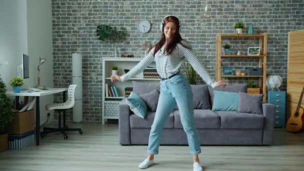 Mujer feliz bailarina con auriculares bailando en apartamento solo divirtiéndose — Vídeos de Stock